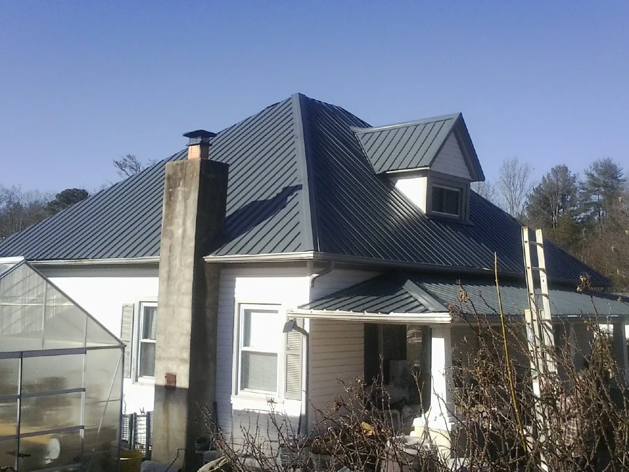 Dark blue standing seam metal roof on a white farmhouse with dormer — Slate & Tile Roof Repair by Roofing Brothers in Brigham City