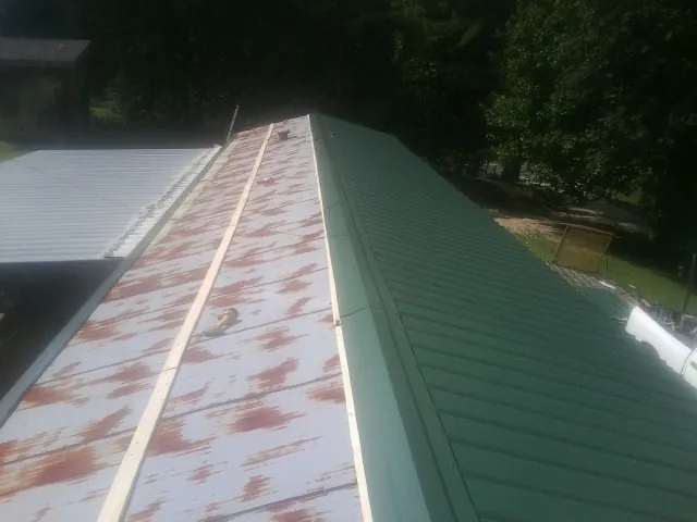 Old rusted panels beside newly installed green metal roofing — Wind Damage Roof Repair by Roofing Brothers in Brigham City
