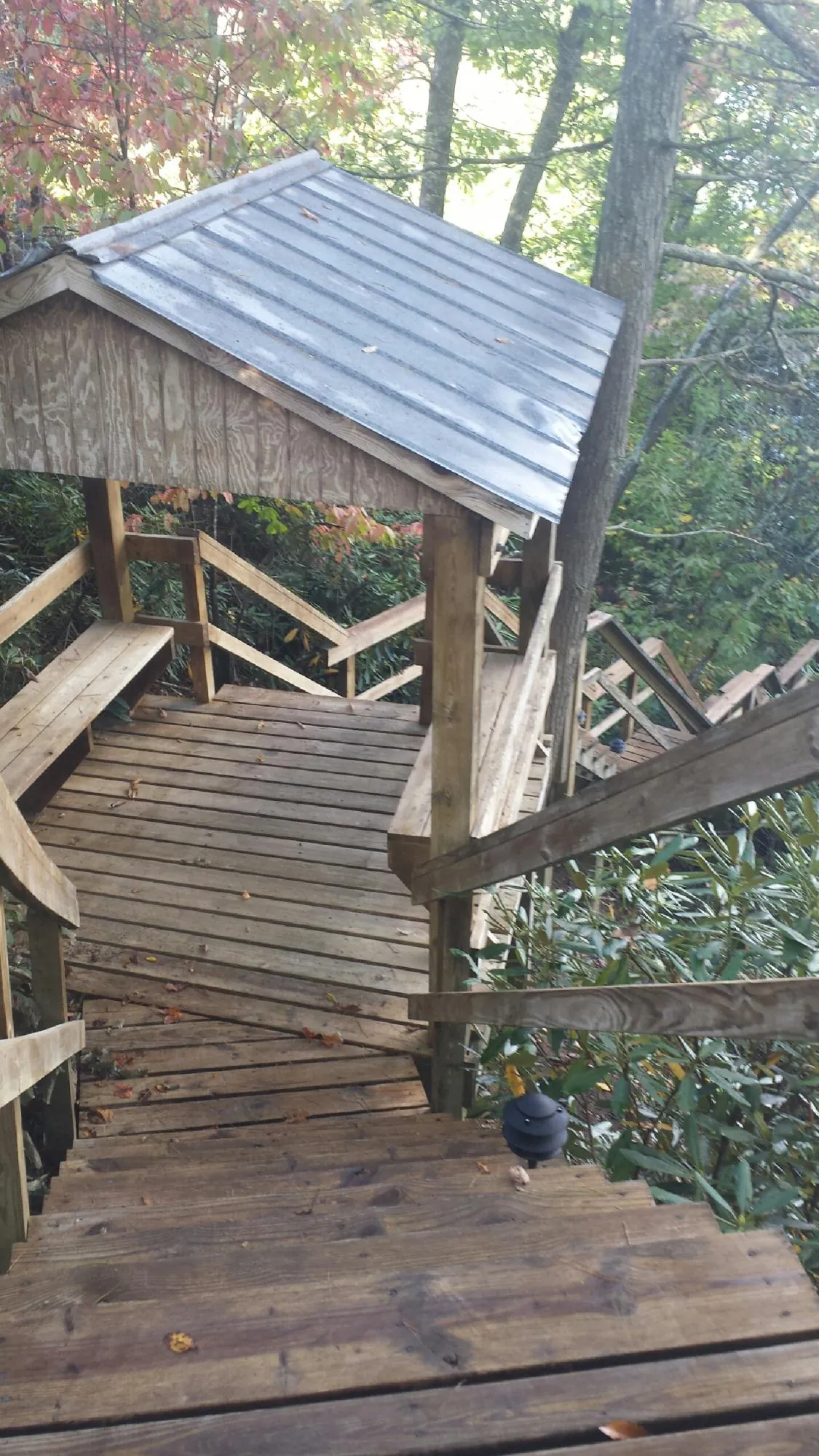 Metal roofed shelter over wooden steps on a wooded walkway — Skylight Repair & Installation work by our crew in Brigham City